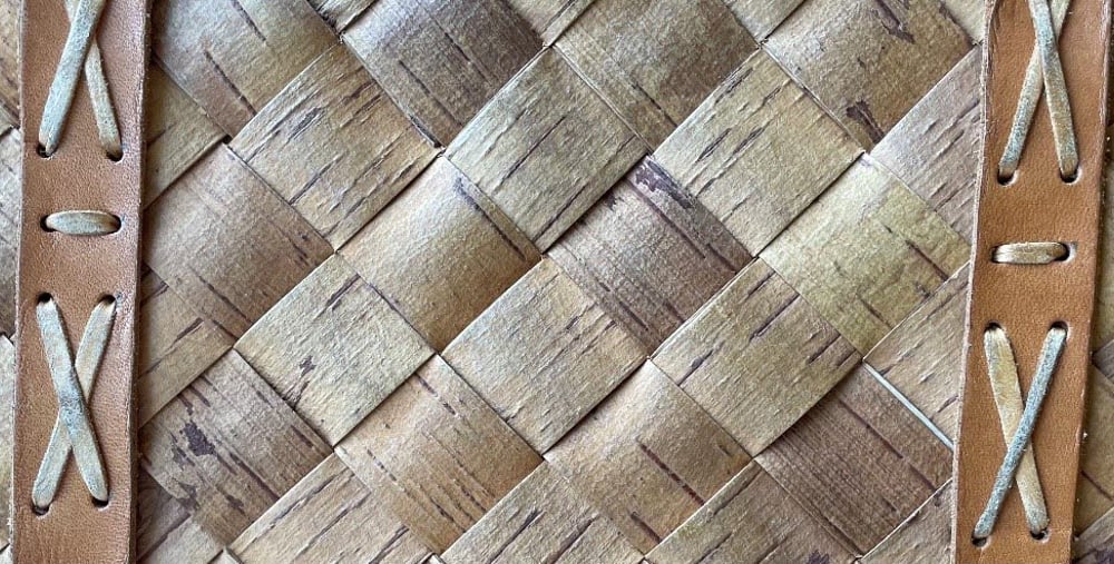 Närbild av flätat trämaterial med läderremmar.