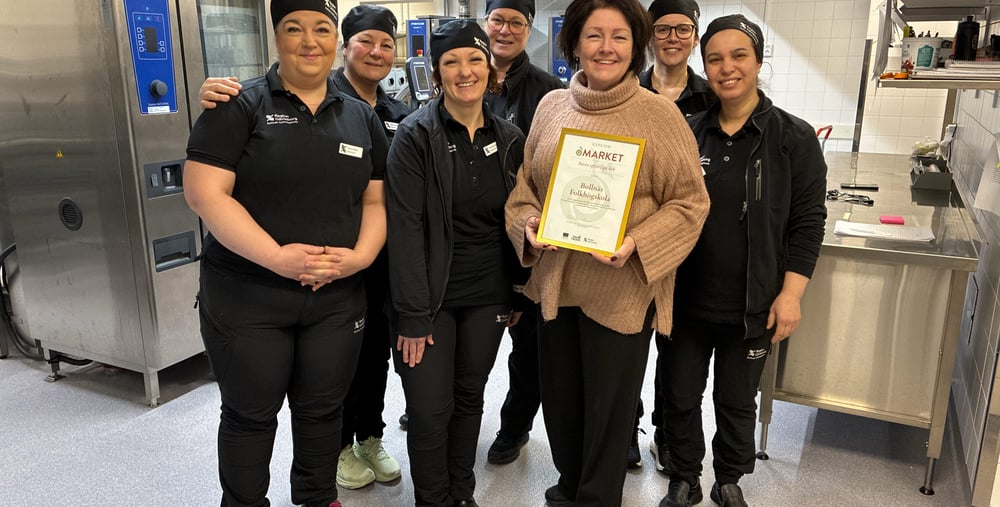 Sju personer står uppradade bredvid varandra i ett stort restaurangkök. 