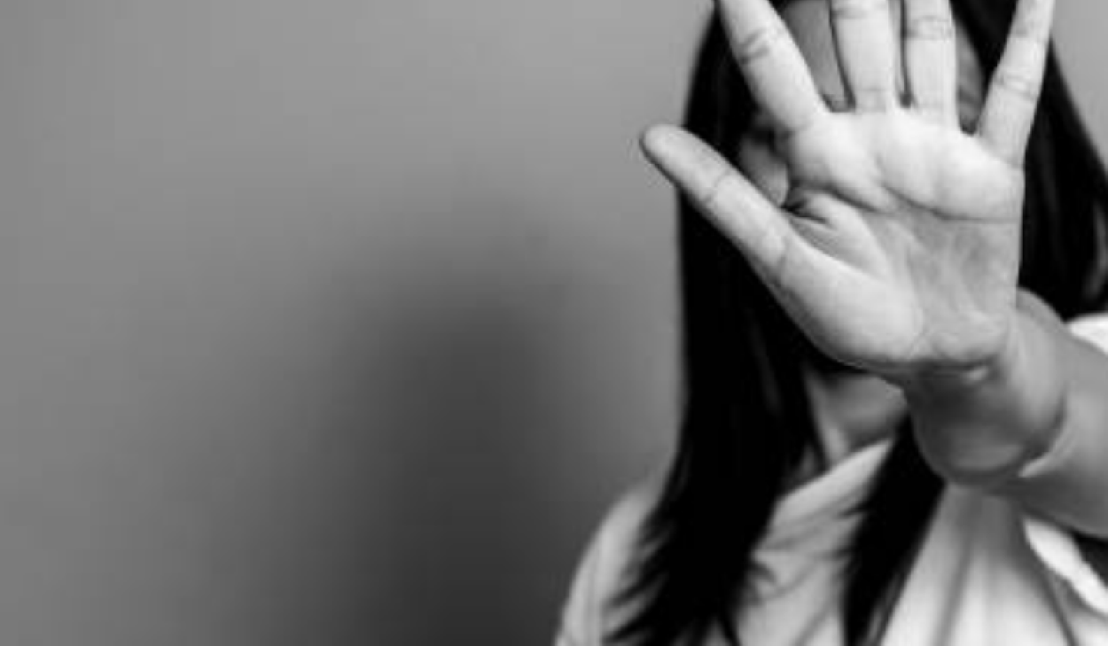 En person håller upp handen mot kameran med handflatan framåt, vilket delvis skymmer ansiktet.