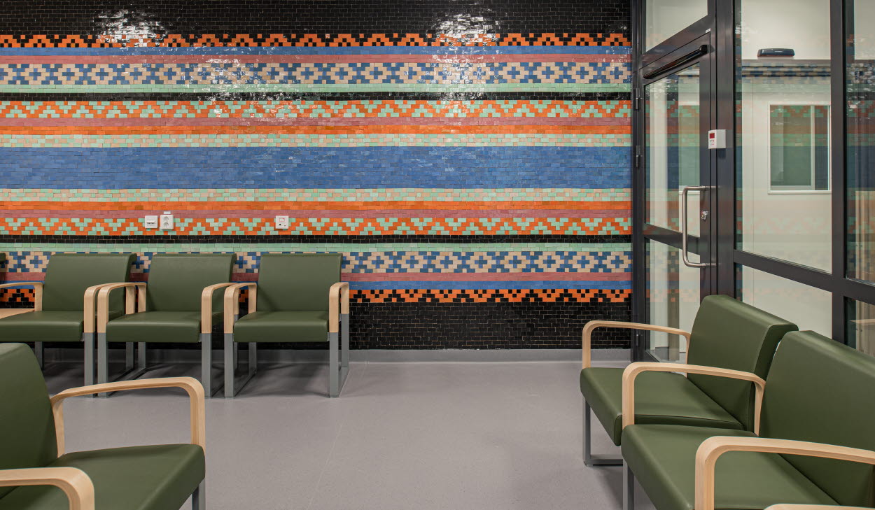 Konstverk på en hel vägg av Ylva Ceder i ett väntrum med stolar