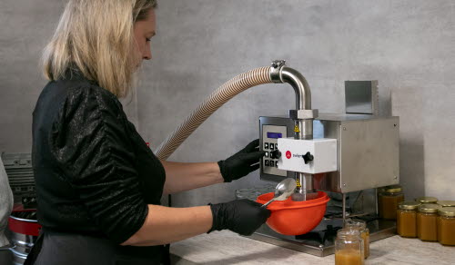 Kvinna tappar honung på burk.