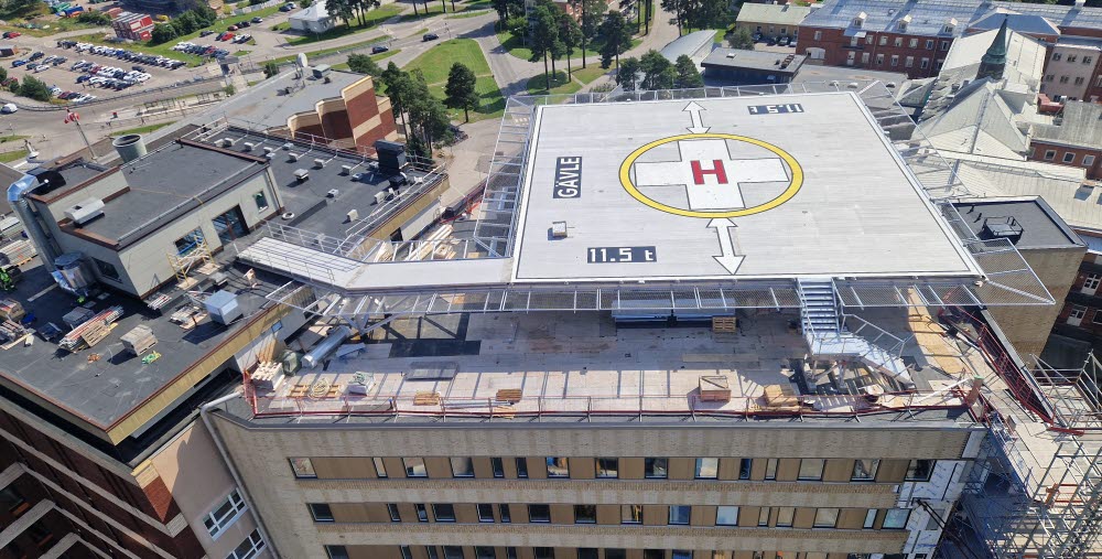 Bilden visar den nya helikopterplattan på taket av hus 60. Helikopterplattan är fortfarande en byggarbetsplats. Bilden visar också en del av den ny tillbyggnaden av 6 våningar och den nya fasaden på den södra sidan av byggnaden. 