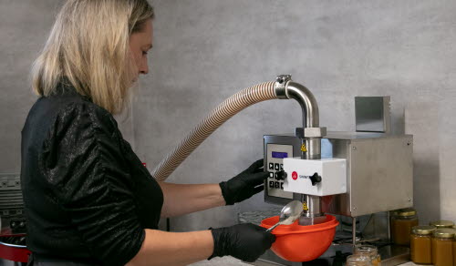 Kvinna tappar honung på burk.